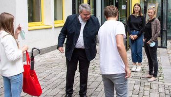 Domkapitular Clemens Bieber (Mitte) überreicht Lena Krückel (links) und Tom Glaser (rechts im Vordergrund) zum Start ihrer Ausbildung die obligatorische Caritas-Tasche mit praktischen Dingen für den Büroalltag. 